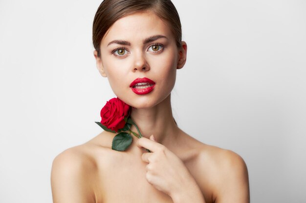 Photo woman with red flower look forward clear skin charm red lips background