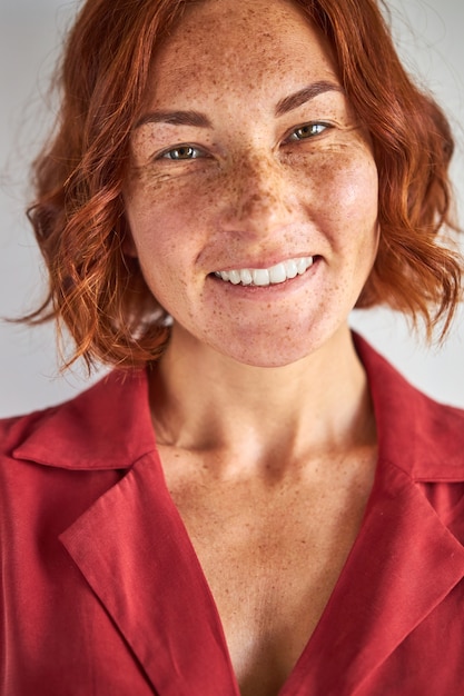 Photo woman with red hair and green eyes posing, smiling at camera in studio, people