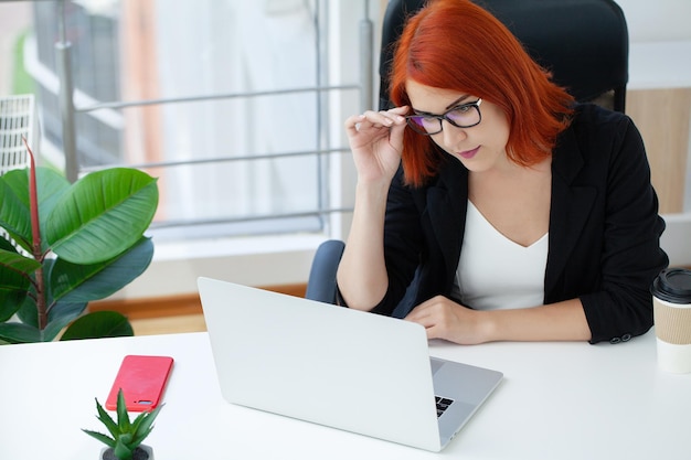 A woman with red hair is talking on the phone in the office