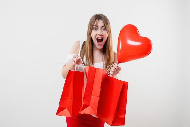 Woman with red heart shaped balloon and shopping bags isolated