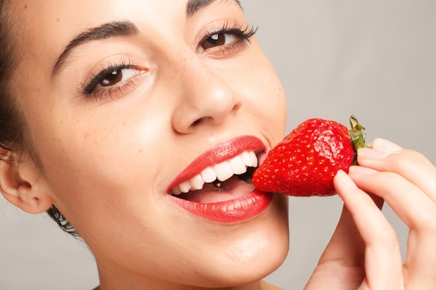 Woman with red lips eating strawberry