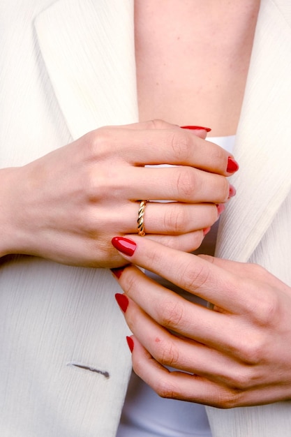 a woman with red nail polish holds her hands with a gold ring on the finger