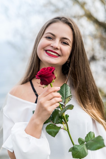 woman with red rose posing outdoors