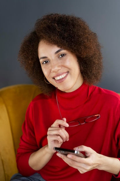 A woman with a red turtleneck and glasses smiles at the camera