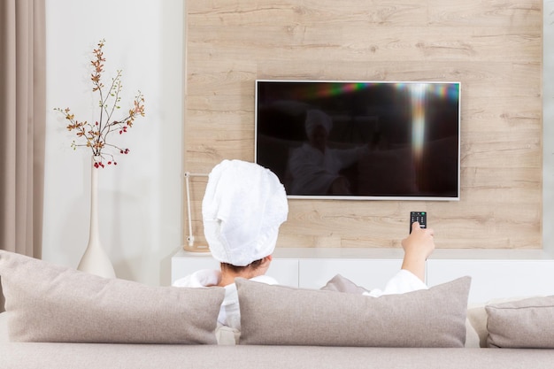 Woman with remote control sitting on couch