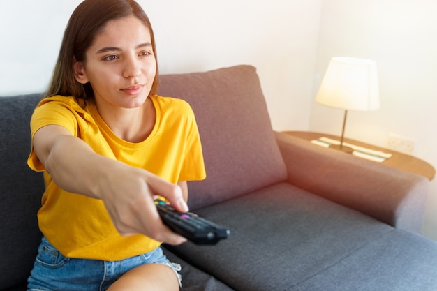 Photo woman with remote control on a sofa in her living room