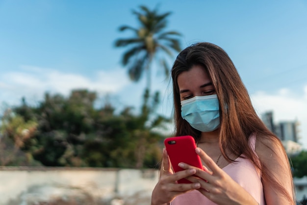 Woman with respiratory mask holding a cell phone