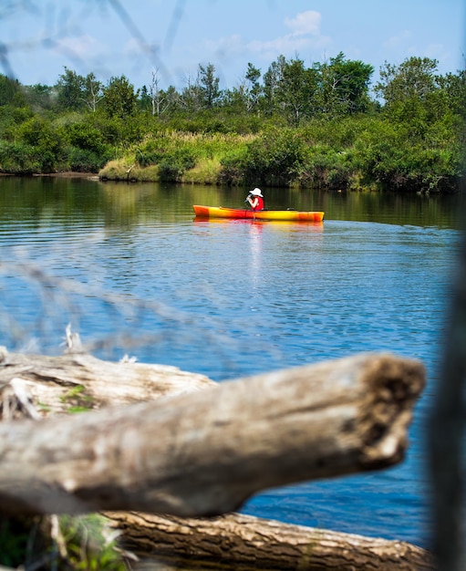 Woman with safety vest kayaking alone on a calm river