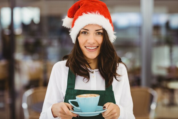 コーヒーを保持しているサンタ帽子の女