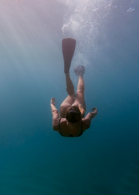 Foto donna con attrezzatura subacquea nuotare nell'oceano