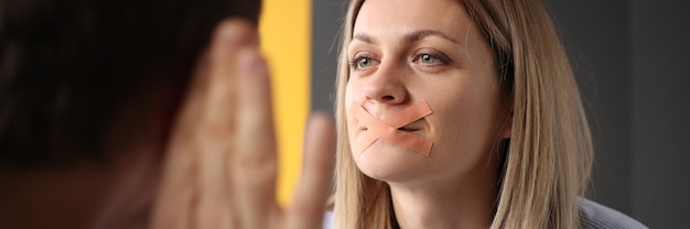 Woman with sealed mouth is trying to say something to man