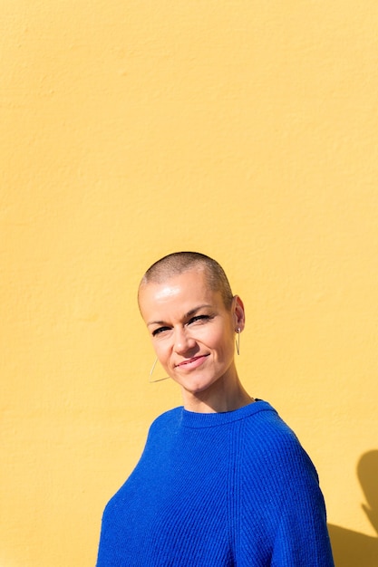 Woman with a shaved head smiling looking at camera