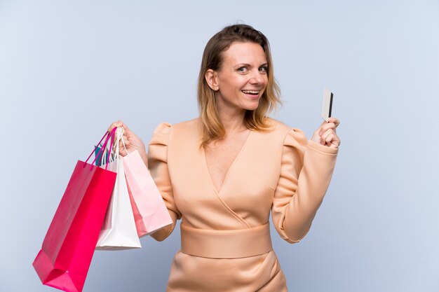 Woman with shopping bags over isolated blue wall