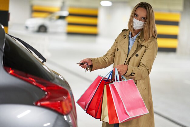 woman with shopping bags in mask in underground parking lot