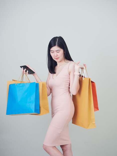 Woman with shopping bags standing against gray background