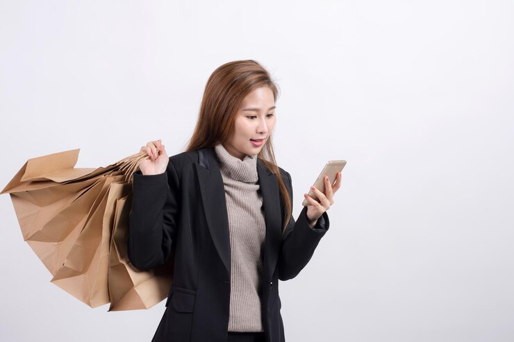 Photo 有購物袋的女人用智能手機站在白色的背景下