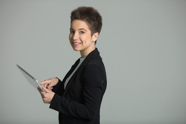 woman with short hair on her head, in a suit with a tablet in her hands