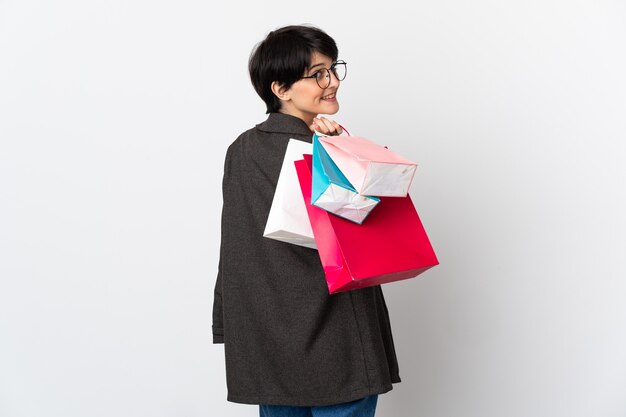 Woman with short hair over isolated holding shopping bags and smiling