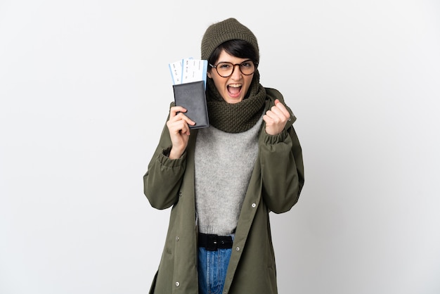 Женщина с короткими волосами над изолированной стеной счастлива в отпуске с паспортом и билетами на самолет