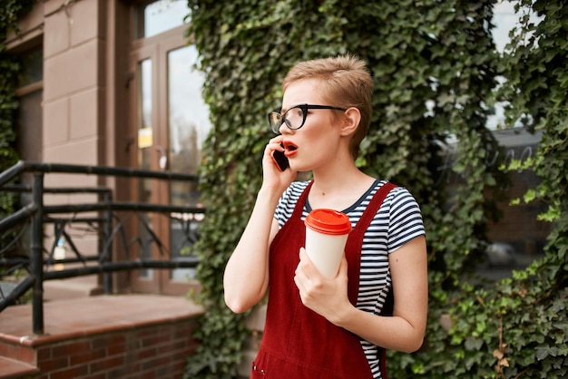 写真 高品質の写真で通りで電話で話しているメガネをかぶった短の女性