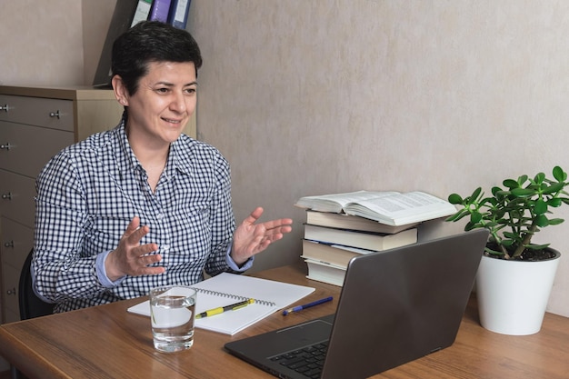 Woman with a short haircut spread her hands during an online working meeting