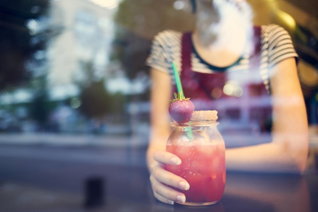 Foto una donna con i capelli corti si siede in un caffè da sola con un cocktail foto di alta qualità