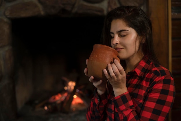 Woman with siberian husky dog sitting on the wooden floor in front of the burning fireplace