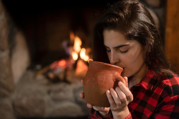 Woman with siberian husky dog sitting on the wooden floor in front of the burning fireplace