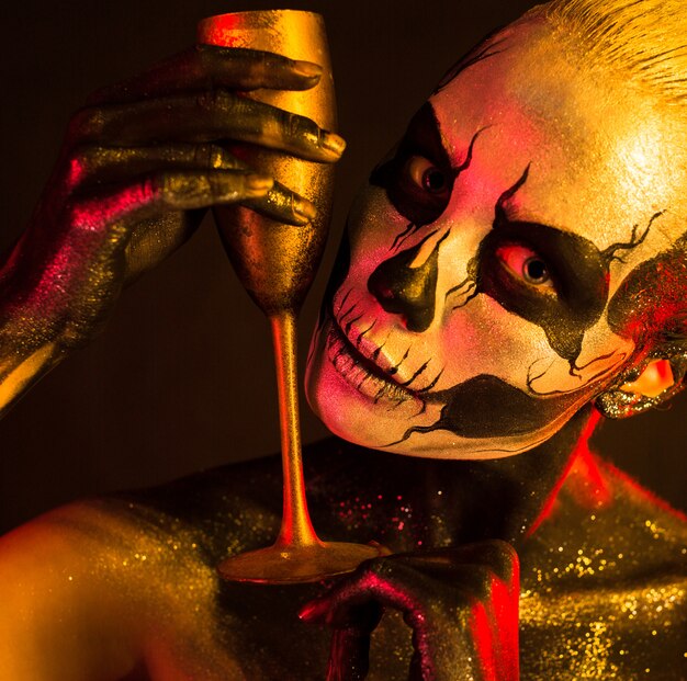 woman with skeleton makeup holds glass