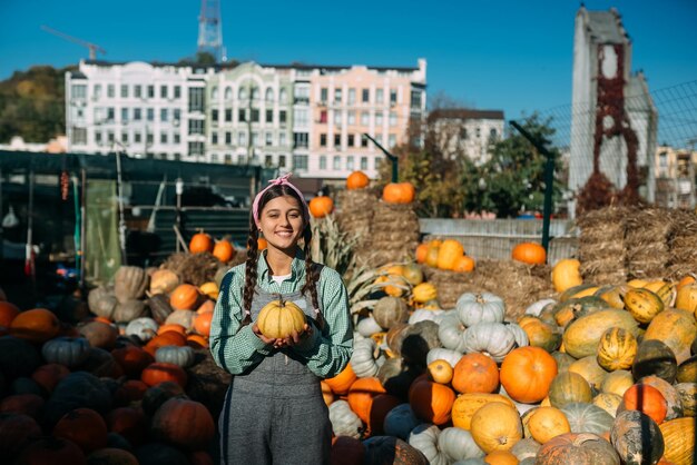 Woman with a small pumpkin among the autumn harvest