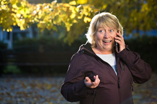 秋の屋外のスマートフォンを持つ女性