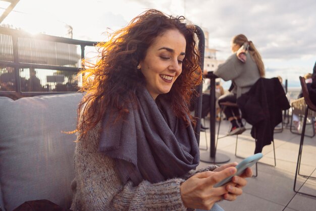 La donna con uno smart phone si siede in una bella terrazza