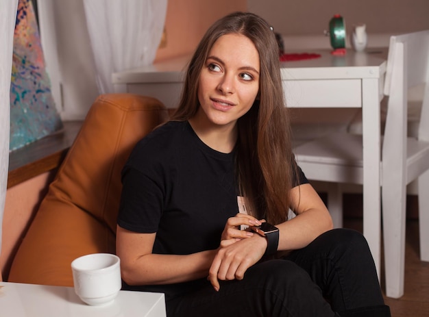 黒のTシャツのカフェでスマートウォッチを持つ女性