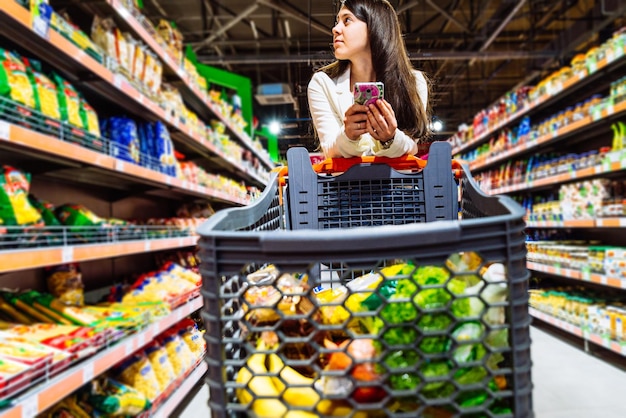 Woman with smartphone in store. grocery shopping. gadgets and shopping.