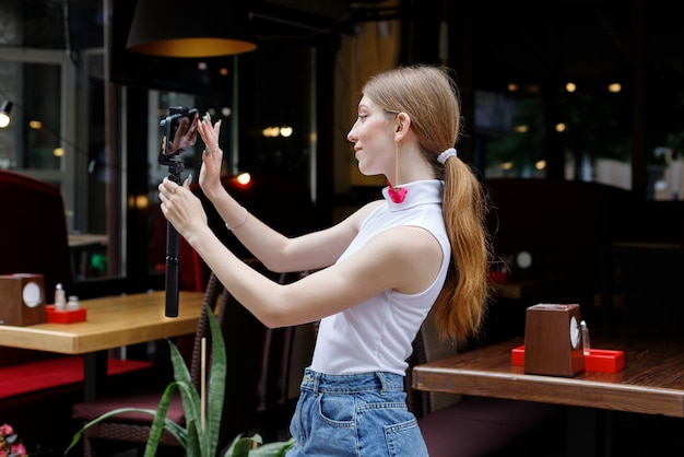 Женщина со смартфоном фотографирует себя в городе летом