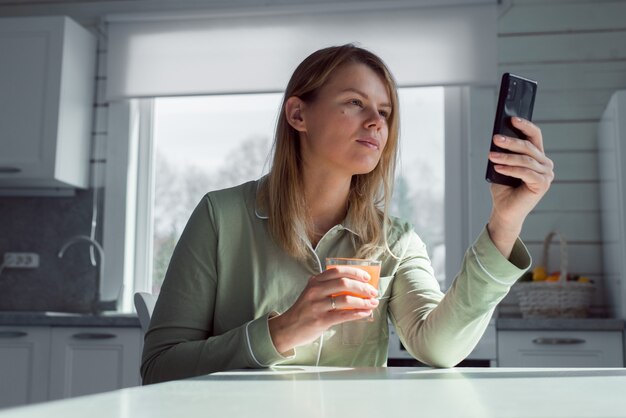 woman with smartphone video chatting or reading at home