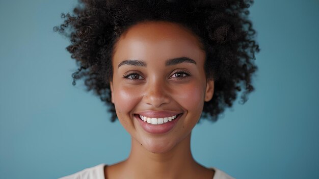 A woman with a smile on her face and a blue background is smiling at the camera and she has a white