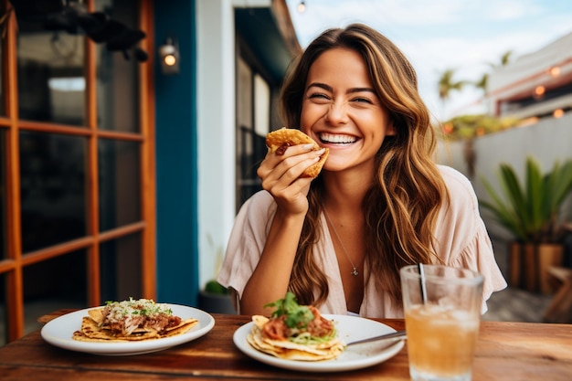 Foto donna con un sorriso che assapora tacos e bevande sul patio di un ristorante