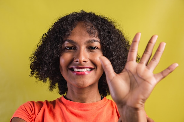 Woman with smiling afro style making a high five with her hand.