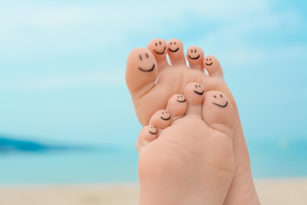 Woman with smiling faces drawn on toes outdoors closeup of feet Space for text