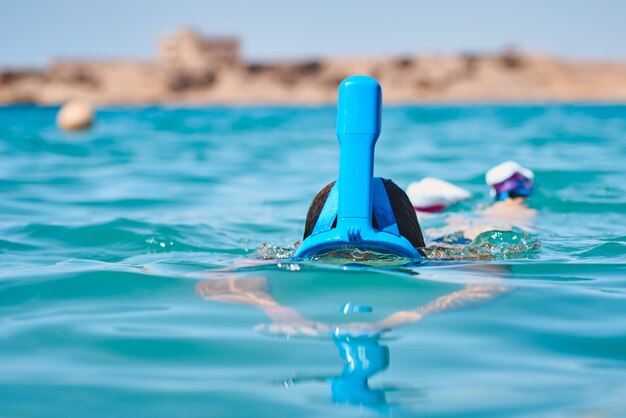 青い海でダイビングシュノーケルフルフェイスマスクを持つ女性。夏休み