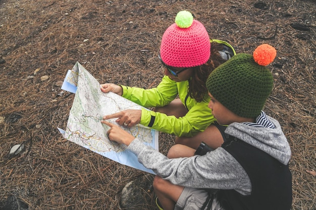 Foto donna con figlio che legge una mappa nella foresta