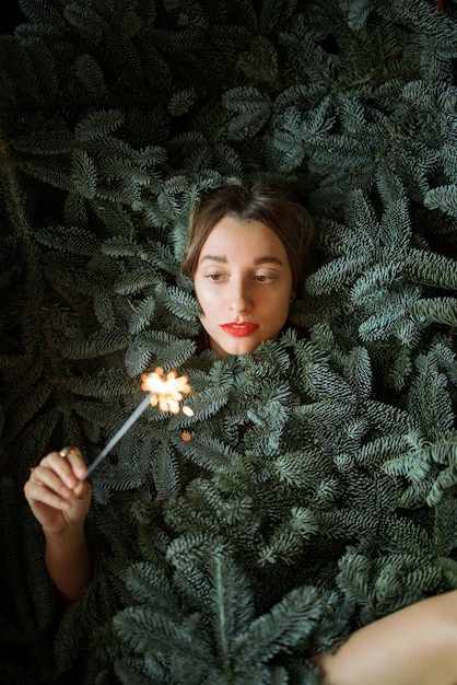 Woman with sparkler covered with nobilis branches