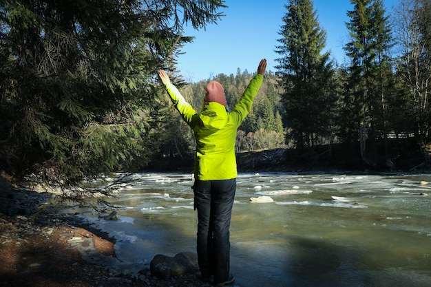 Woman with spread hands standing near river