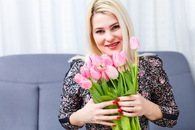 Woman with Spring Flower bouquet. Happy surprised model woman smelling flowers. Mother's Day. Springtime