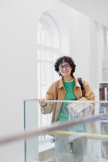 Woman with stack of books in hands in library or coworking successful female student