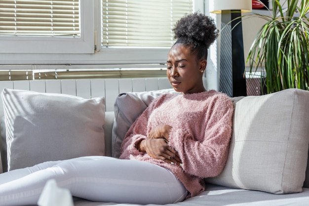 Photo woman with a stomach ache lying on sofa