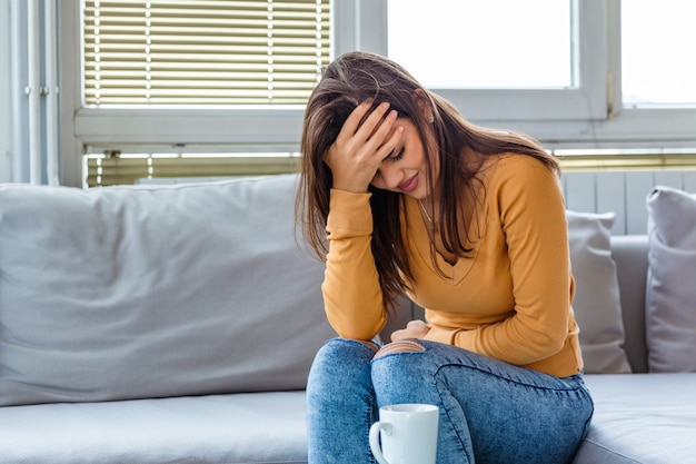 woman with a stomach ache sitting on the sofa