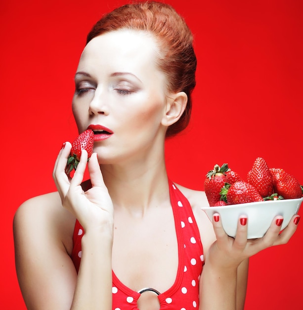 Woman with strawberry on the red background