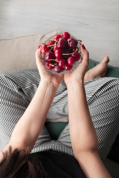 Woman with striped pants and a bowl of red fresh and ripe cherries